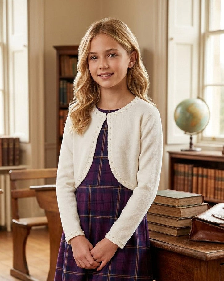 Carriage Boutique ivory knit bolero sweater with pearl trim worn by a young girl over a purple plaid dress