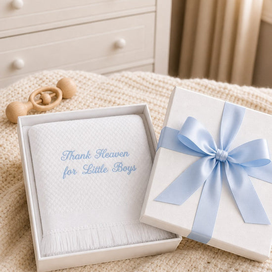 Carriage Boutique Julius Berger white baby blanket with blue embroidery in a gift box with a blue ribbon.
