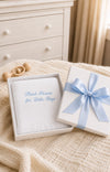 Carriage Boutique Julius Berger white baby blanket with blue embroidery in a gift box with a blue ribbon.