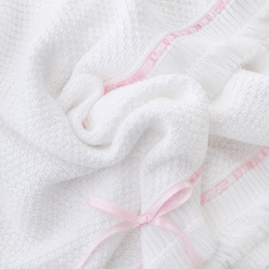 Carriage Boutique Julius Berger white knit baby blanket with delicate pink satin ribbon trim and a sweet bow accent.