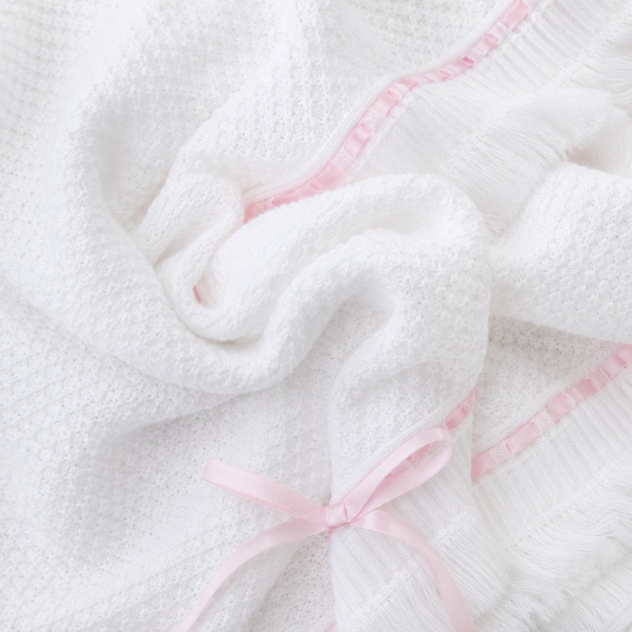 Carriage Boutique Julius Berger white knit baby blanket with delicate pink satin ribbon trim and a sweet bow accent.