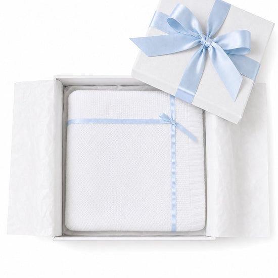 Carriage Boutique Julius Berger white knit baby blanket with blue satin ribbon trim and bow in a gift box