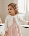 Carriage Boutique toddler girl wearing a white Julius Berger bolero sweater with pearl trim over a pink dress