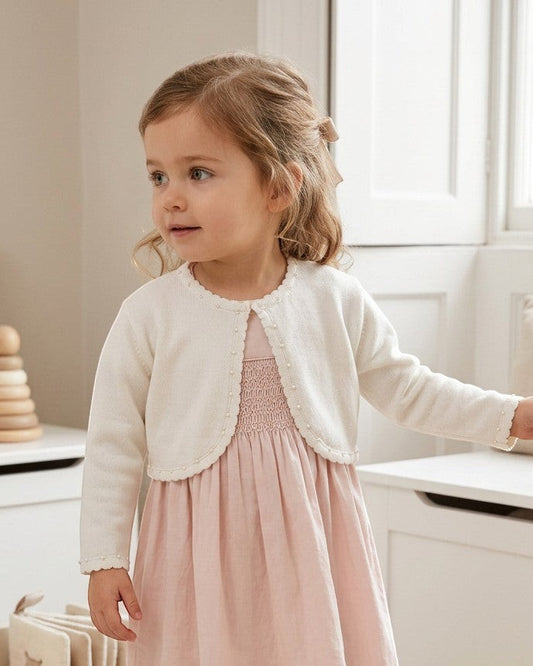 Carriage Boutique toddler girl wearing a white Julius Berger bolero sweater with pearl trim over a pink dress