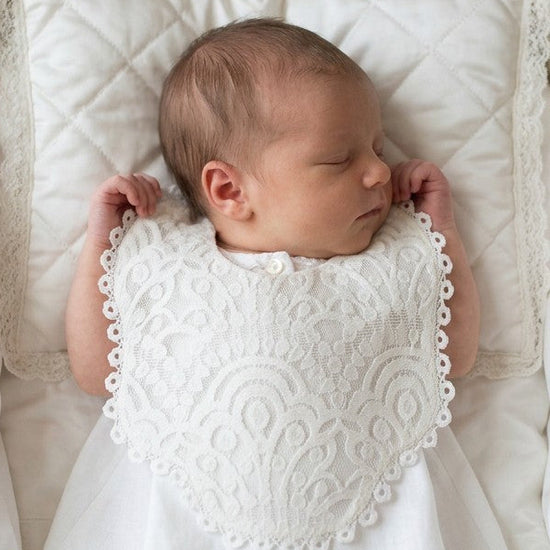 Carriage Boutique white lace christening bib on a sleeping newborn baby in a vintage bassinet