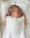 Carriage Boutique white lace christening bib on a sleeping newborn baby in a vintage bassinet