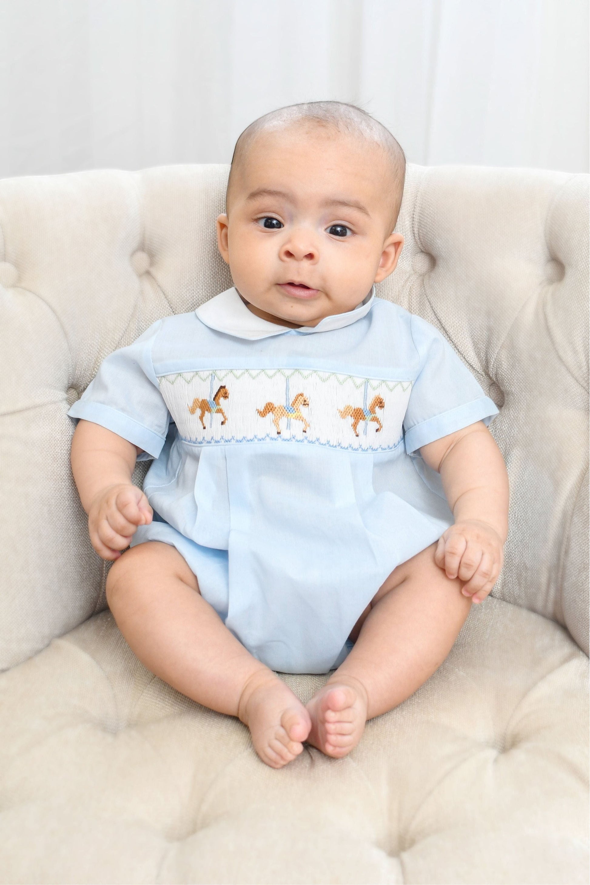 Carriage Boutique light blue smocked bubble romper with carousel horse embroidery and Peter Pan collar.