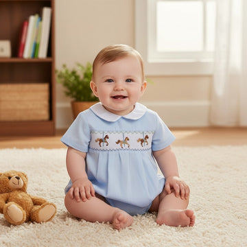 Carriage Boutique light blue smocked bubble romper with carousel horse embroidery and Peter Pan collar on a baby.