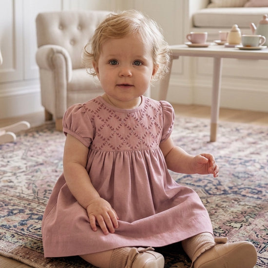 Carriage Boutique mauve suede-like baby dress with smocked yoke and delicate embroidery, worn by a toddler.