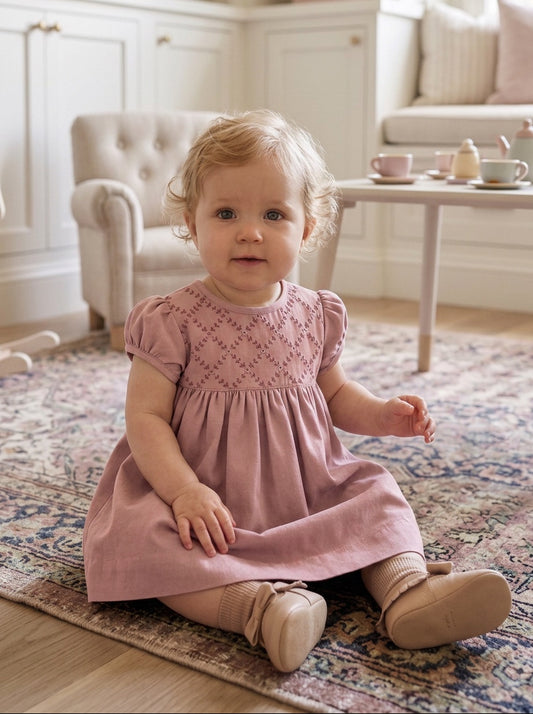 Carriage Boutique mauve suede-like baby dress with smocked yoke and delicate embroidery, worn by a toddler.