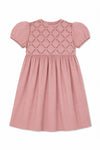 Carriage Boutique mauve baby dress with short sleeves, smocked yoke, and delicate hand embroidery on soft fabric.