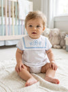 Carriage Boutique baby boy white bubble romper with blue trim, Peter Pan collar, and custom monogram in a nursery.