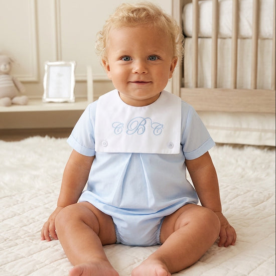 Carriage Boutique baby boy light blue cotton bubble romper with a white monogrammed bib collar in a nursery setting.