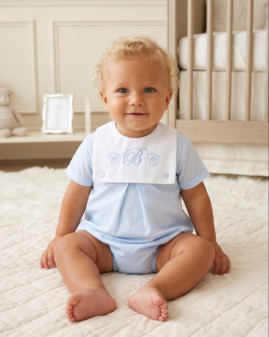 Carriage Boutique baby boy light blue cotton bubble romper with a white monogrammed bib collar in a nursery setting.