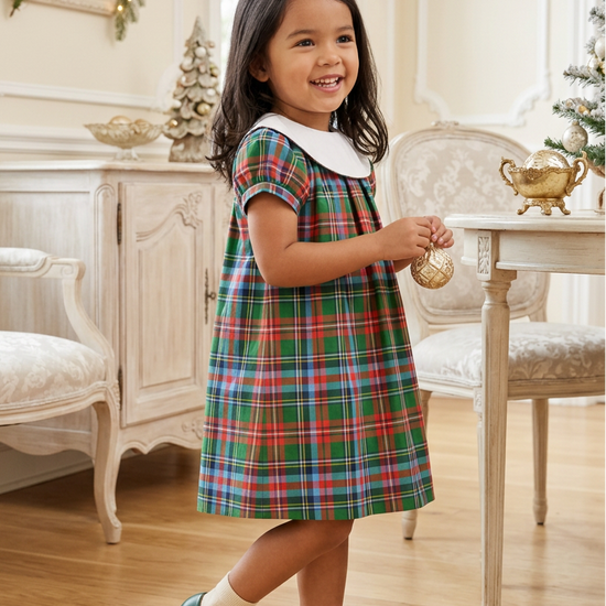 Carriage Boutique toddler girl wearing a multicolor plaid cotton dress with a white Peter Pan collar in a room