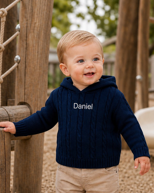 Carriage Boutique navy cable knit baby sweater with hood and custom Daniel embroidery on chest worn by a toddler