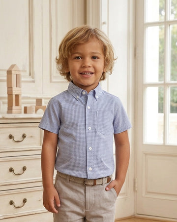 Carriage Boutique toddler boy wearing a navy blue check short-sleeve button-down shirt with khaki pants