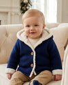 Carriage Boutique navy knit cotton baby jacket with sherpa lining and hood worn by a toddler sitting on a sofa