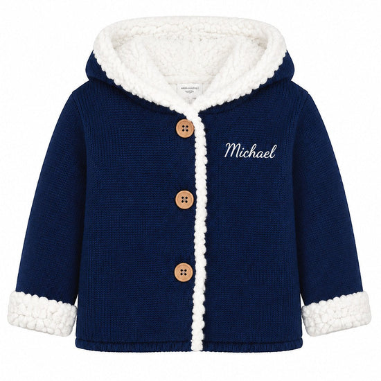 Carriage Boutique navy knit cotton baby jacket with white sherpa lining, hood, and wooden button front closure.
