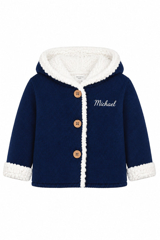 Carriage Boutique navy knit cotton baby jacket with white sherpa lining, hood, and wooden button front closure.