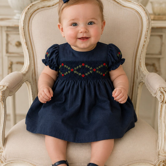 Carriage Boutique navy silk baby dress with smocked floral embroidery, puffy sleeves, and a matching hair bow.