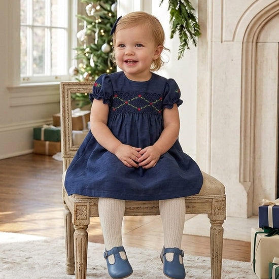 Carriage Boutique navy blue silk baby girl dress with smocked floral detail, puffy sleeves, and a round neckline.