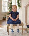 Carriage Boutique navy blue silk baby girl dress with smocked floral detail, puffy sleeves, and a round neckline.