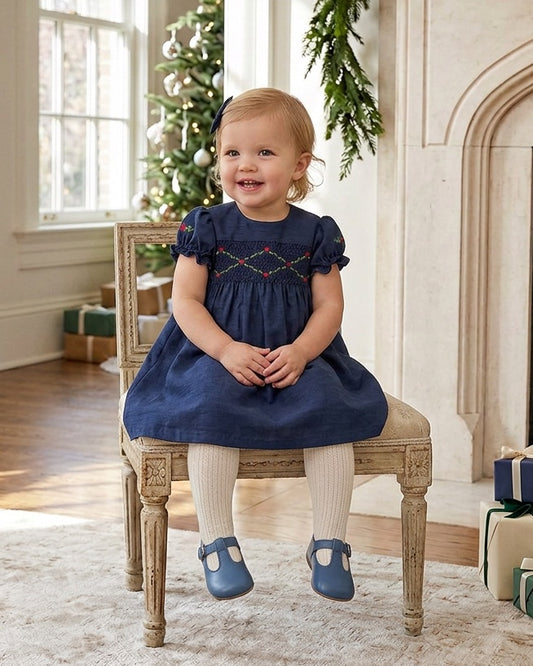 Carriage Boutique navy blue silk baby girl dress with smocked floral detail, puffy sleeves, and a round neckline.