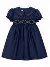 Carriage Boutique navy toddler dress with smocked floral embroidery, puffy sleeves, and a round collar.
