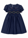 Carriage Boutique navy blue toddler party dress with smocked floral embroidery, puffy sleeves, and a round collar.