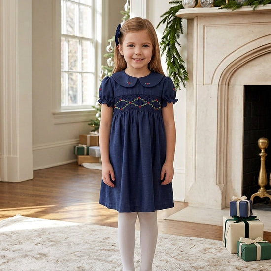 Carriage Boutique navy blue toddler party dress with smocked floral collar and puffy sleeves in a festive room