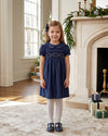 Carriage Boutique navy blue toddler party dress with smocked floral collar and puffy sleeves in a festive room