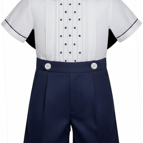 Carriage Boutique navy tucks with dots baby boy suit. White short-sleeve shirt with pintucks, navy dots, Peter Pan collar, and navy piping. Navy shorts with pleats and white buttons.