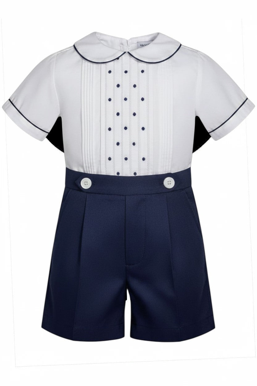 Carriage Boutique navy tucks with dots baby boy suit. White short-sleeve shirt with pintucks, navy dots, Peter Pan collar, and navy piping. Navy shorts with pleats and white buttons.