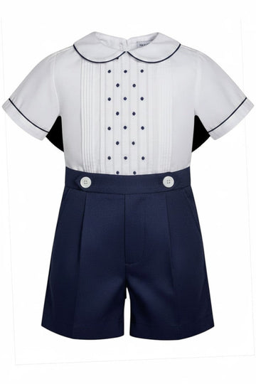 Carriage Boutique navy tucks with dots baby boy suit. White short-sleeve shirt with pintucks, navy dots, Peter Pan collar, and navy piping. Navy shorts with pleats and white buttons.