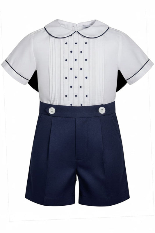 Carriage Boutique navy tucks with dots baby boy suit. White short-sleeve shirt with pintucks, navy dots, Peter Pan collar, and navy piping. Navy shorts with pleats and white buttons.