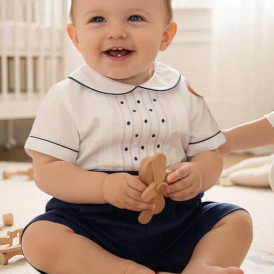 Carriage Boutique navy tucks with dots bobbie suit: white short-sleeve shirt with pintucks, navy dots, Peter Pan collar, and navy shorts.