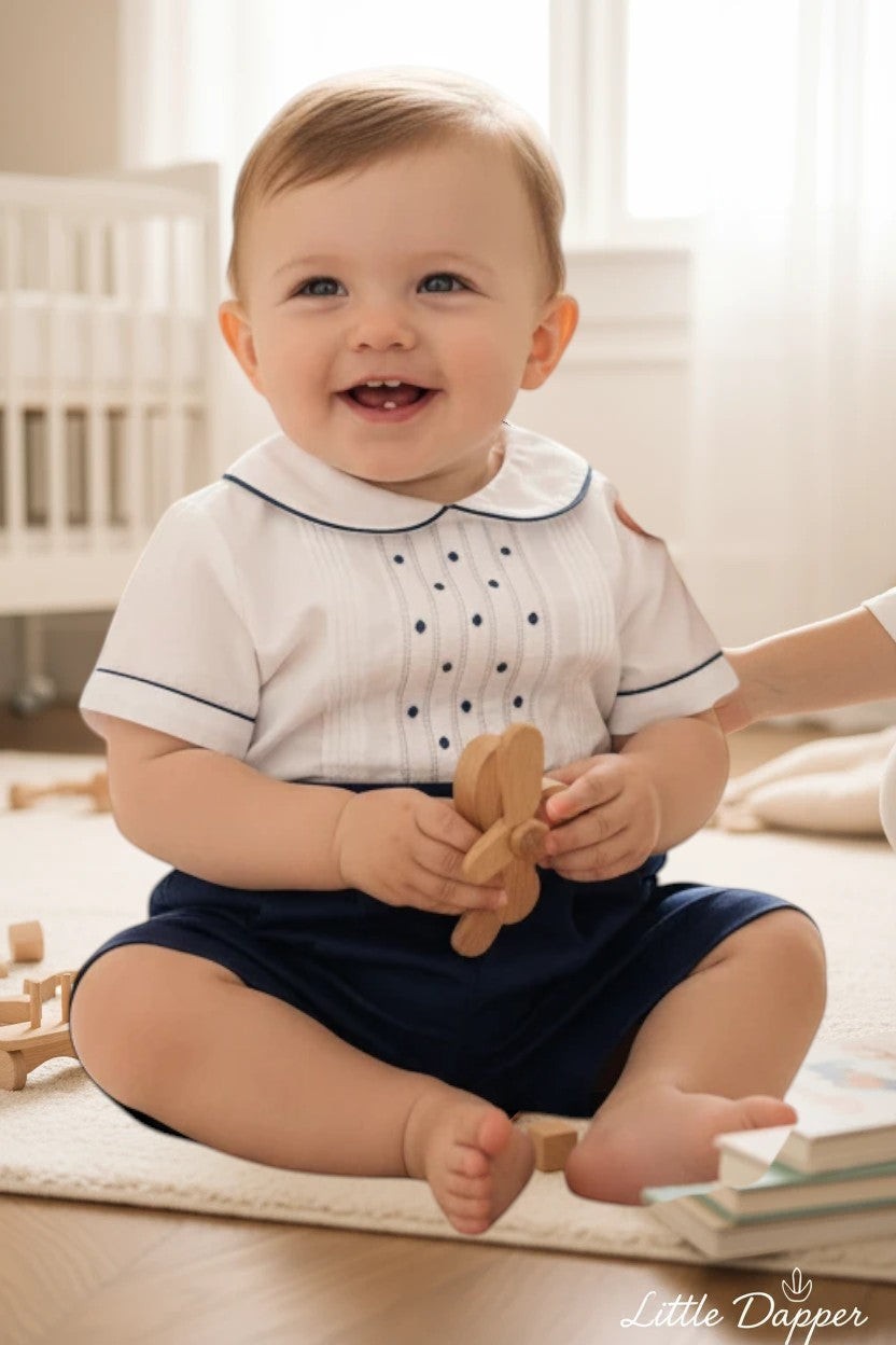 Carriage Boutique navy tucks with dots bobbie suit: white short-sleeve shirt with pintucks, navy dots, Peter Pan collar, and navy shorts.