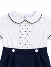 Carriage Boutique baby bobbie suit featuring a white shirt with navy pintucks, dot embroidery, and navy piping details.
