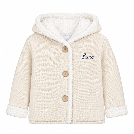 Carriage Boutique off-white knit cotton baby jacket with sherpa lining, hood, three front buttons, and Luca embroidery.