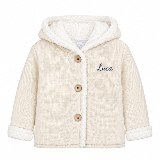 Carriage Boutique off-white knit cotton baby jacket with sherpa lining, hood, three buttons, and Luca monogram.