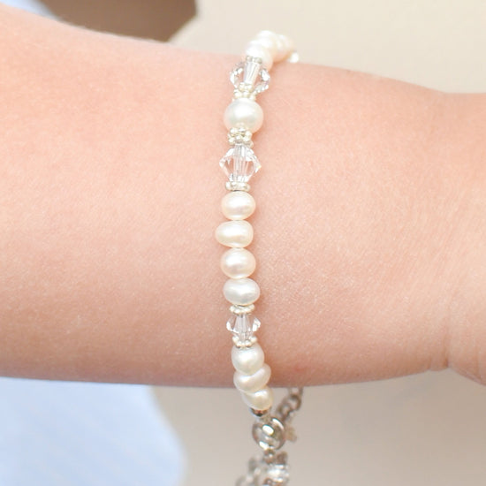Carriage Boutique sterling silver baby cross bracelet with freshwater pearls and crystals on a child's wrist