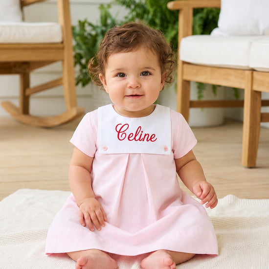 Carriage Boutique personalized baby girl dress in light pink cotton with a white button bib and red monogramming.