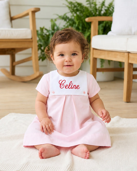 Carriage Boutique personalized baby girl dress in light pink cotton with a white button bib and red monogramming.