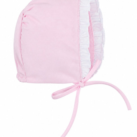 Carriage Boutique baby girl bonnet in soft pink fabric with white ruffled trim and tie closure for Easter.
