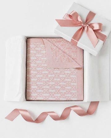 Carriage Boutique pink and white cotton baby blanket with monogram pattern in a gift box with a satin ribbon.