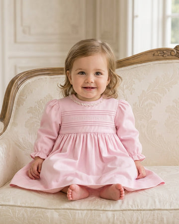 Carriage Boutique light pink cotton baby dress with long puffy sleeves, lace collar, and hand-embroidered pin tucks.