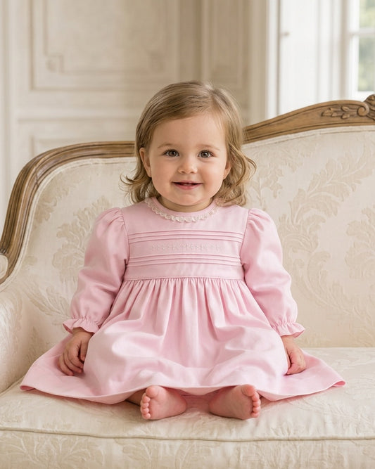 Carriage Boutique light pink cotton baby dress with long puffy sleeves, lace collar, and hand-embroidered pin tucks.