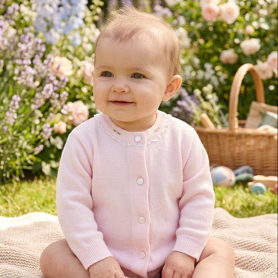 Carriage Boutique baby girl wearing a soft pink cotton cardigan with delicate embroidered rosebuds and button closure.