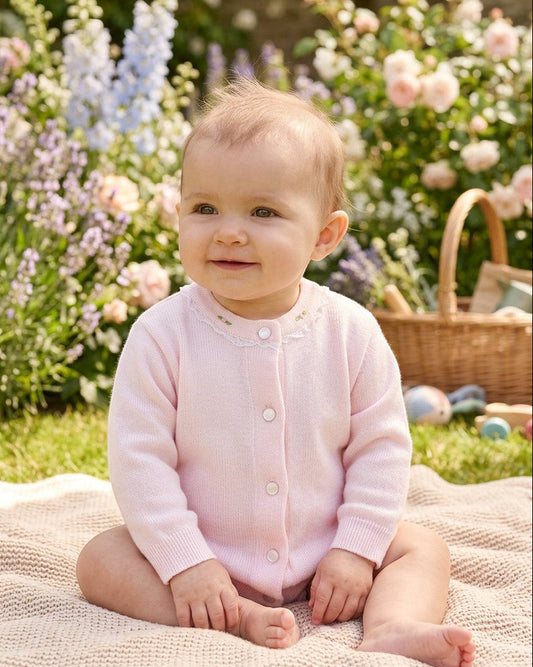 Carriage Boutique baby girl wearing a soft pink cotton cardigan with delicate embroidered rosebuds and button closure.
